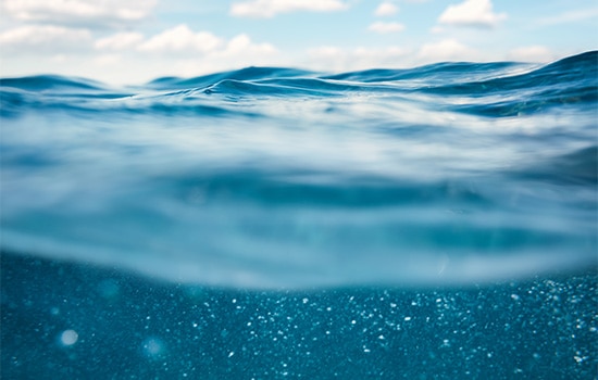 Foto von Meereswellen mit blauem Himmel, aus dem Wasser heraus aufgenommen